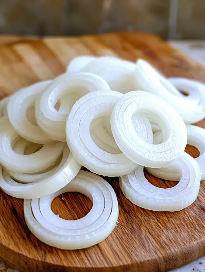 Slice onions into ½-inch thick rings and pair similar sizes together. Cut mozzarella into strips and sandwich them between two onion rings to form a filled ring.