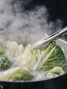 Bring a large pot of water to a boil. Remove the core of the cabbage and place the whole head into the boiling water. Boil for 3-5 minutes, then carefully peel off the softened leaves.