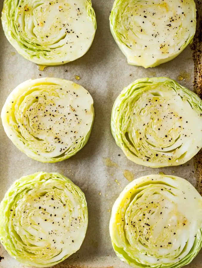 Slice the cabbage into thick 1-inch rounds. Place on a baking tray lined with parchment paper. Brush with olive oil and season with salt and pepper.