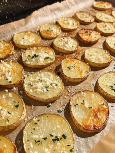 In a large bowl, toss the potatoes with olive oil, garlic powder, oregano, thyme, salt, pepper, and half the Parmesan.