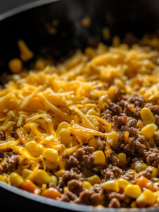 In a skillet, brown the ground beef over medium-high heat until fully cooked. Add diced onion and minced garlic, cook until soft and fragrant.
